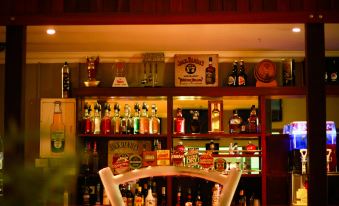 a bar with a variety of bottles and glasses , as well as a dining table at Ravenswood Hotel