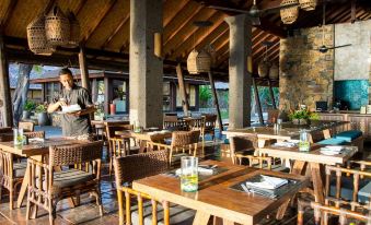 a man wearing a chef 's hat is standing near a restaurant table , holding a wine glass at Jeeva Klui Resort