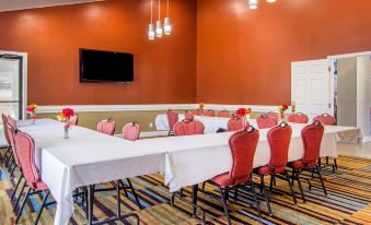a conference room with a long table and chairs , a television on the wall , and pendant lights at Quality Inn
