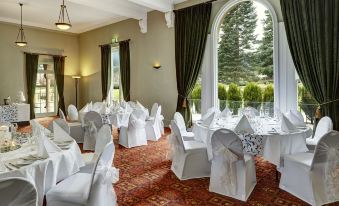 a well - decorated banquet hall with tables covered in white tablecloths and chairs arranged for a formal event at Hanmer Springs Hotel
