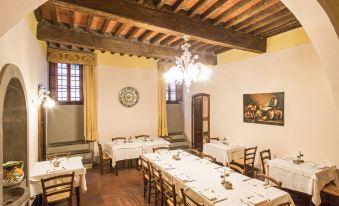 a dining room with multiple tables , chairs , and a chandelier hanging from the ceiling , decorated with yellow walls and paintings at Palazzo Leopoldo Dimora Storica & Spa