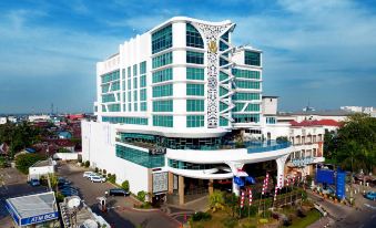 a tall , modern building with a unique design is situated in a bustling city area at Galaxy Hotel Banjarmasin