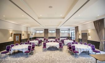 a large banquet hall with multiple round tables and chairs arranged for a formal event at Denham Grove