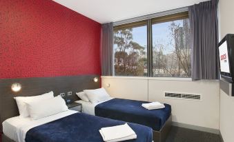 a hotel room with two beds , a window offering a view of the city , and white towels on the beds at Space Hotel