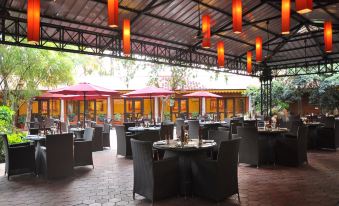 an outdoor dining area with tables and chairs , as well as umbrellas for shade at Aalankrita Resort and Convention