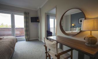 a modern bedroom with a large window , wooden desk , and mirror , as well as a chair in the room at Highfield Hotel