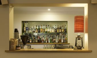 "a well - stocked bar with various bottles of alcohol , including some labeled "" cocktail "" and "" gin ,"" as well as a coffee" at Athelstane Hotel