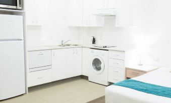 a small kitchen with white cabinets , a refrigerator , and a microwave , connected to a bedroom with a bed at Copacabana Shores