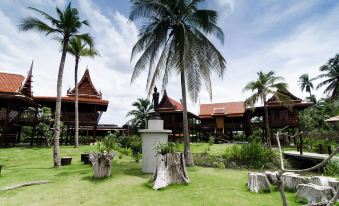 a lush green lawn with palm trees in the background , creating a tropical atmosphere at a resort at Maikaew Damnoen Resort