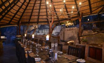 a large dining table set up for a formal dinner , with multiple chairs arranged around it at Amalinda Lodge