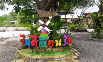 "a colorful windmill sculpture in a grassy area surrounded by rocks , with the word "" happy "" written on it" at Sampaongern Home Stay