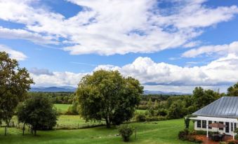 a beautiful countryside scene with a blue sky , green trees , and fluffy clouds in the distance at Whitford House