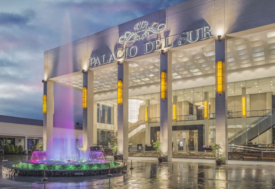 a grand building with a fountain in front of it , illuminated by the lights of a fountain at Marcian Garden Hotel