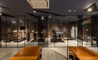 a modern gym with large glass windows , wooden tables , and comfortable seating , set against a dark background at Green Hotel