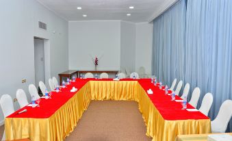 a conference room with a long table covered in red and gold tablecloths , set up for a meeting at Aracan Pyramids Hotel
