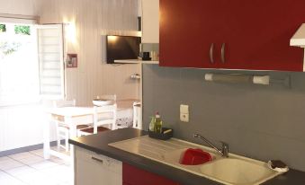 a kitchen with a sink , cabinets , and a television mounted on the wall next to a dining table at Le Bellevue