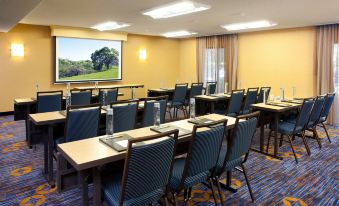 a conference room with rows of chairs arranged in a semicircle , and a projector screen mounted on the wall at Courtyard Pleasanton