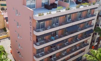 "a pink building with the word "" hotel "" written on it , surrounded by trees and other buildings" at Best Western Astoria