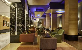 a modern hotel lobby with various seating options , including couches , chairs , and a dining table at Taj Club House