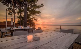 a wooden table with a candle on it is set up outside near the ocean at Poseidon Hotel