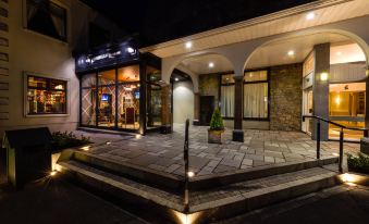 a nighttime scene of a building with a fountain in front , illuminated by lights and surrounded by trees at The Inn at Dromoland