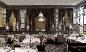 a restaurant with black curtains , white tablecloths , and tables set for dining , along with chairs at Hotel d'Angleterre