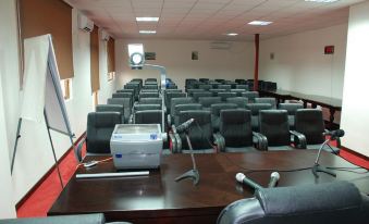 a large conference room with multiple chairs arranged in rows , along with a projector and microphones on the table at Richmond Hotel