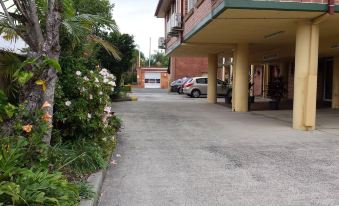 a residential area with a brick building and a parking lot filled with cars , flowers , and trees at The Mullum Motel