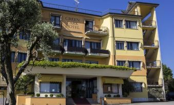 a large hotel building with multiple balconies and windows , situated on a street with trees and a clear blue sky at Green Park Hotel