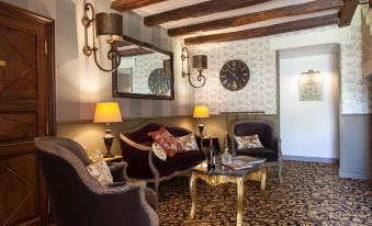 a cozy living room with two couches , a coffee table , and a clock on the wall at Hôtel Saint-Martin - la Maison Younan