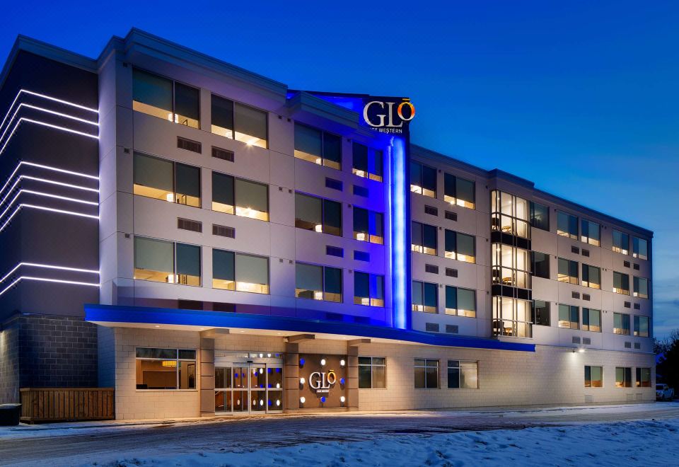 "the exterior of a hotel named "" glo "" lit up with blue lights against a dark sky" at GLo Best Western Kanata Ottawa West
