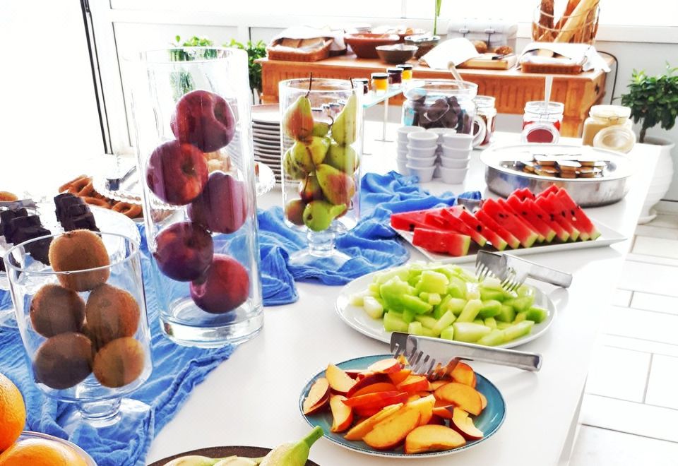 a table is set with various fruits , including apples , oranges , and pears , as well as bowls of different types of food at Saint George Hotel