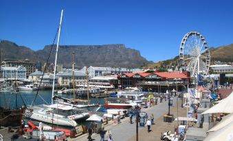 a bustling harbor with numerous boats , including sailboats , and people walking around , near the water 's edge at Fountains Hotel