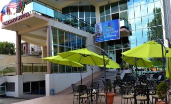 an outdoor dining area with umbrellas , chairs , and tables set up in front of a building at Delano Hotel Bahir Dar