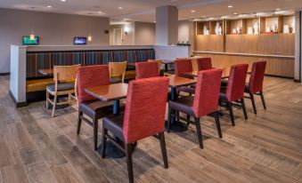 a modern restaurant with wooden floors , red chairs , and a large counter , possibly for serving or dining at TownePlace Suites Merced