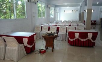 a conference room set up for a meeting , with tables and chairs arranged in rows at Losmen Kebun Indah
