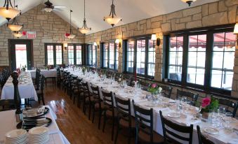 a long dining table with white tablecloths and chairs , set for a formal event , in a stone room with large windows at Le Viking Resort & Marina