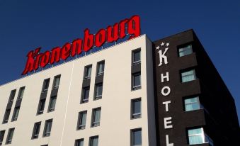 "a tall hotel with a red sign that reads "" rheinburg "" and a k hotel sign in front" at K Hotel