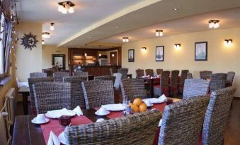 a restaurant with wooden tables and chairs , a red tablecloth , and a fruit display on the table at Relax Inn