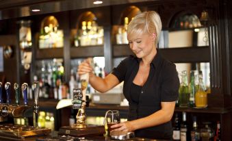a woman in a black shirt is pouring beer from a tap at a bar at The Horseshoe Country Inn