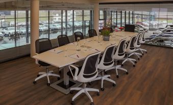 a conference room with a long table , chairs , and several wine glasses is shown with large windows at Self Check-in Hotel Von Rotz