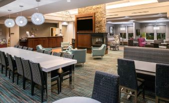 a hotel lobby with a large dining area , featuring tables and chairs , a fireplace , and comfortable seating at Residence Inn Waynesboro