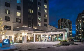 a modern hotel building with multiple entrances and a blue umbrella in front of it at Delta Hotels by Marriott Waterloo