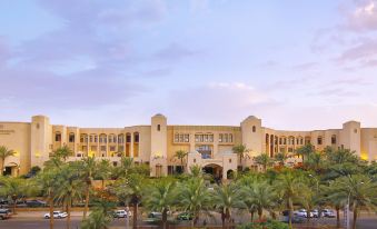 a large , ornate hotel building surrounded by palm trees and cars parked in front of it at InterContinental Hotels Aqaba (Resort Aqaba)