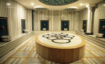 a large , circular room with a marble floor and a central rug featuring an olympic symbol at Sunprime C-Lounge