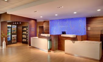 a modern hotel reception area with wooden flooring , a blue waterfall wall , and multiple computer monitors at Comfort Suites