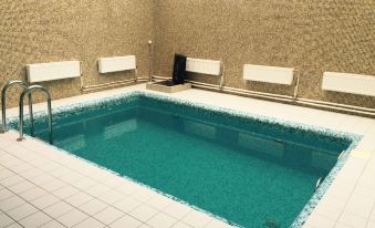 an empty swimming pool surrounded by tiles , with several benches placed around it for seating at Mayak