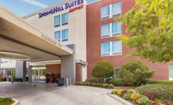 the exterior of a springhill suites by marriott hotel , with its entrance and parking lot at SpringHill Suites Houston the Woodlands