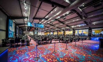a large room with rows of chairs and tables , a colorful carpet , and banners on the walls at Kings Casino & Hotel