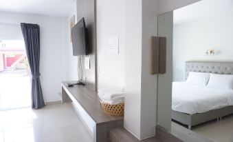 a modern hotel room with a large flat - screen tv mounted on the wall , a bed , and a mirror at Porjai Resort Uthai Thani